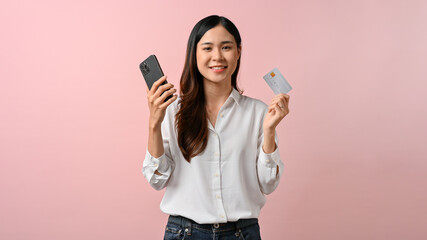 Image of young Asian woman holding smartphone and credit card