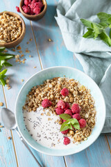 Healthy breakfast cereal bowl homemade granola with fresh raspberry and chia seeds on a rustic table. Diet nutrition concept.