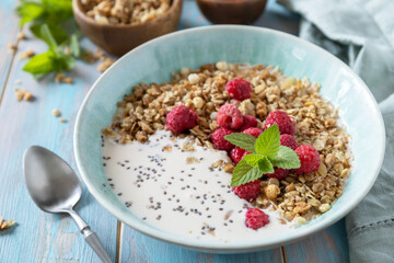 Diet nutrition concept. Healthy breakfast cereal bowl homemade granola with fresh raspberry and chia seeds on a rustic table.