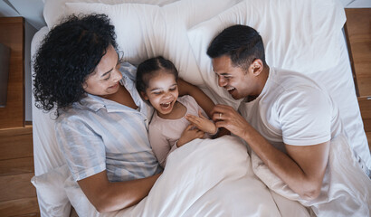 Mom, dad and child tickle in a bedroom bed in the morning at family home with bonding. Laughing, mother and father with a young girl being playful and happy with a smile and youth together with love - obrazy, fototapety, plakaty
