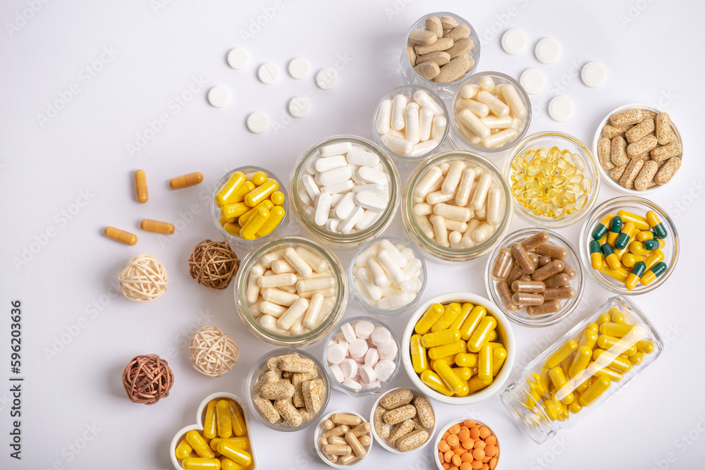 Wall mural Nutritional supplements, minerals and vitamins in forms of colored pills, tablets and capsules in small jars on hite background from above. A large amount of vitamins.