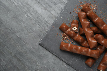 Tasty chocolate bars with nuts on black table, top view. Space for text