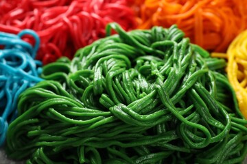 Rolled spaghetti painted with different food colorings as background, closeup