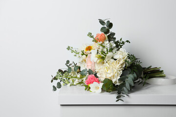 Bouquet of beautiful flowers on wooden table against white wall. Space for text