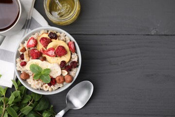Oatmeal with freeze dried fruits, nuts and mint on grey wooden table, flat lay. Space for text