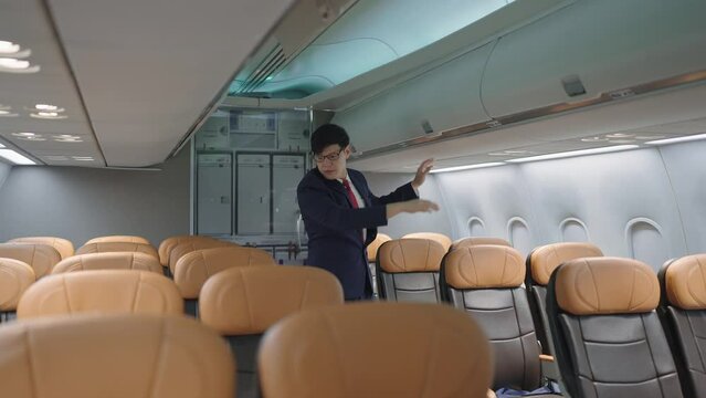 Asian male flight attendant in uniform checking the seat in airplane after passengers arrive at destination and got off the plane 