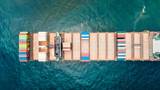 Aerial view on ultra large container vessel from top on scrubber funnel area, cargo space and containers stored on deck, stern of the ship