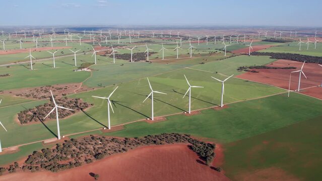 Elevated view of a large group of Wind turbines in a Wind turbines farm turning and producing electricity natural energy at sunset. Numerous windmills spinning in the background, Renewable Wind, Spain