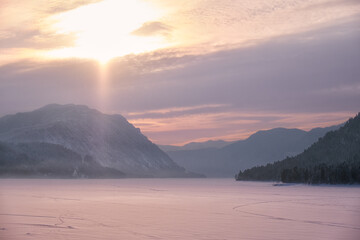 Beautiful sunset over the mountain lake Teletskoe in Altai in winter.