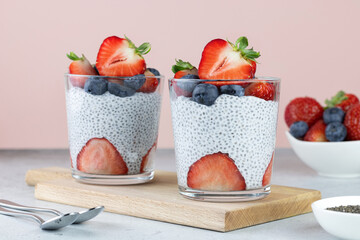 Chia pudding with strawberries and blueberries, chia seeds on a pink background. Healthy breakfast...