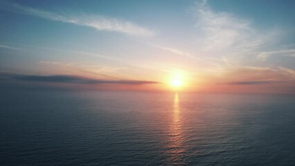 Fixed drone clip showing beautiful pink and orange sunset and reflections in open blue water