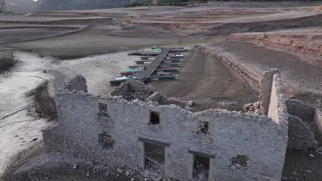 Building ruin and unusable pier on dry shores of Sau swamp in Catalonia, Spain. Aerial forward ascending