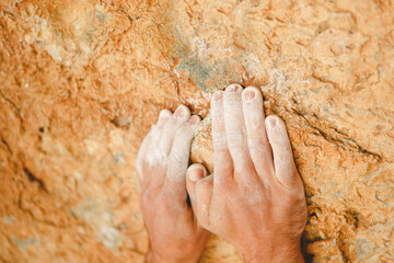 Rock climber's hands grasping handhold on natural cliff