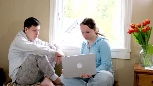 girl and boy teen are sitting at window man looks out young woman at computer to look for ticket to experience resentment communication 