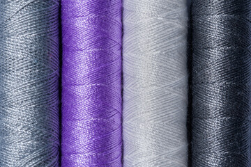 Kolorowe nici nawinięte na szpulki ułożone ściśle obok siebie fotografowane z góry w zbliżeniu makro 