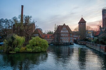 Fototapeta premium Ratsmuhle or old water mill and Wasserturm or water tower on the river Ilmenau in the morning in Luneburg. Germany.