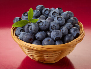 Heidelbeeren im Korb vor rotem Fond