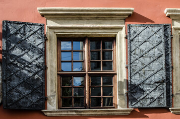 Windows with shutters on the wall of an old house in the center of a European city.