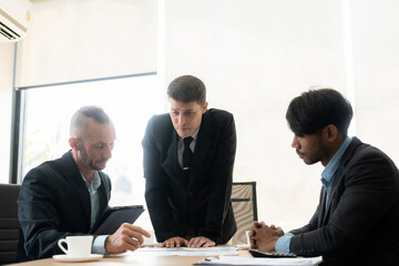 Investment advisor meeting of three businessmen analyzing company financial report, balance sheet, working with chart papers for stock market. Office