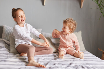 Extremely happy little girls playing in bedroom, laughing loud, being in good playful mood, wearing...