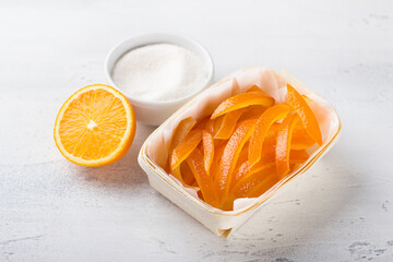 Wicker birch basket with fresh juicy candied oranges with fresh juicy orange and sugar on a light...