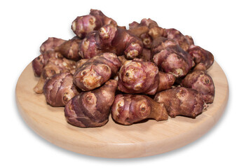 Jerusalem artichoke on a round wooden cutting board isolated on a white background with clipping path.