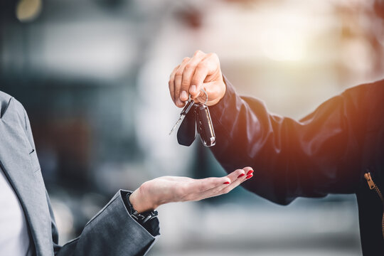 Closeup male hand giving a car key for vehicle loan credit financial, lease or rental concept