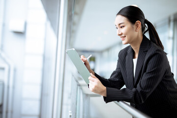 Asian businesswoman holding a tablet looking away , smart business concept.