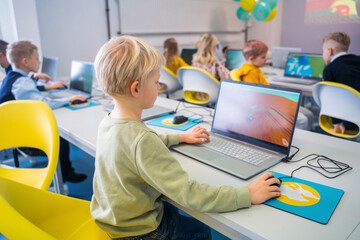 Boy studying through laptop sitting in computer class at school
