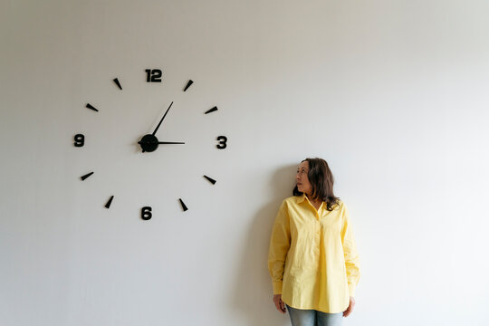 Woman looking at large clock on white wall