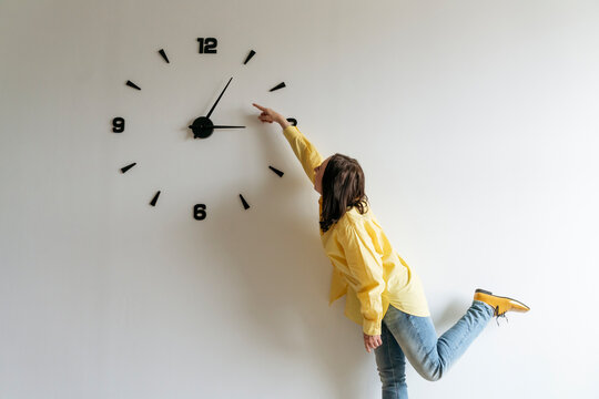 Woman pointing finger on large clock