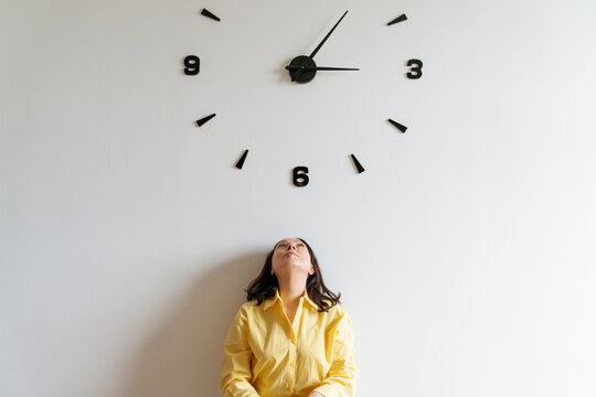 Woman under large clock on wall