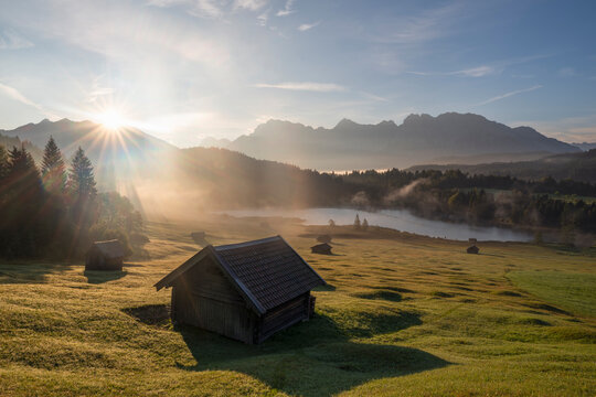Germany, Bavaria, Secluded huts in Karwendel Mountains at foggy sunrise with Geroldsee Lake in background