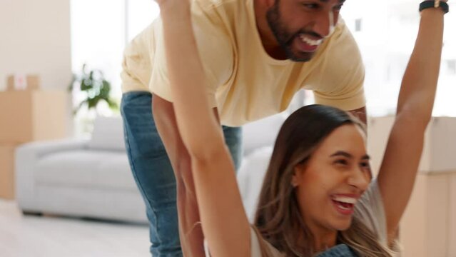 Playful, happy and couple moving into a new home, pushing in box and excited about apartment. Smile, love and and a man and woman playing with boxes, being crazy together and happiness in a house