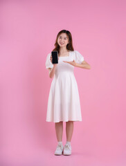 full body image of asian businesswoman using laptop on pink background