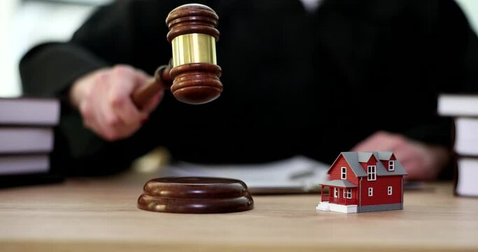 Small toy house standing on judge table closeup 4k movie slow motion. Division of property in divorce concept 