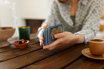 Fortune teller with tarot cards on table near burning candle.Tarot cards spread on table with magic herbs and palo santo aroma sticks. Forecasting concept