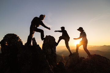 Silhouette of Hikers climbing up mountain cliff.  Concept of help and teamwork, Climbing group...