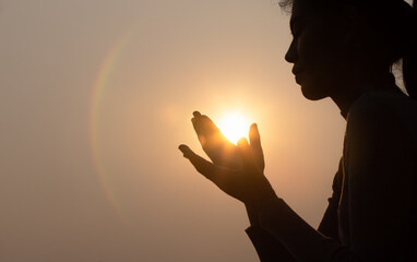 Silhouette of faithful woman praying  at sunset as concept for religion, faith, prayer and...
