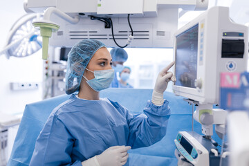 Anesthesiologist keeping track of vital functions of the body during cardiac surgery. Surgeon...