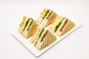 Sandwich with ham, cheese, tomatoes, lettuce, and toasted bread. Front view isolated on white background.