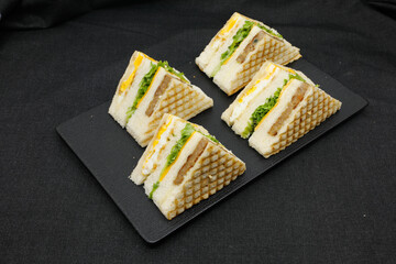 Sandwich with ham, cheese, lettuce, and toasted bread. Front view isolated on black background.