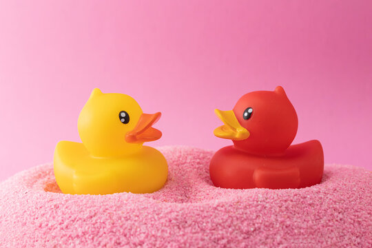 A toy duck on pink sand