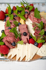 Antipasto set plate. Cold smoked meat plate. Antipasto with ham, prosciutto, salami, blue cheese, mozzarella with blueberries and strawberries. Close up