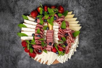 Antipasto set plate. Cold smoked meat plate. Antipasto with ham, prosciutto, salami, blue cheese, mozzarella with blueberries and strawberries. Top view