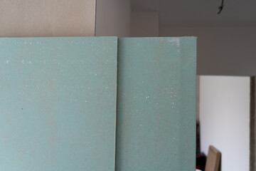 Green waterproof drywall or greenboard. Paper faced gypsum board, moisture proof plasterboard building material. Panel used in construction of interior walls and ceilings. - obrazy, fototapety, plakaty