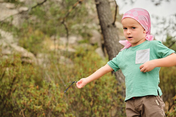 Boy with pink scarf playing in nature