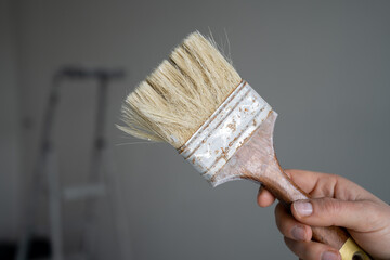 Hand holding decorators' brush, used for painting and decorating of buildings or home interior...