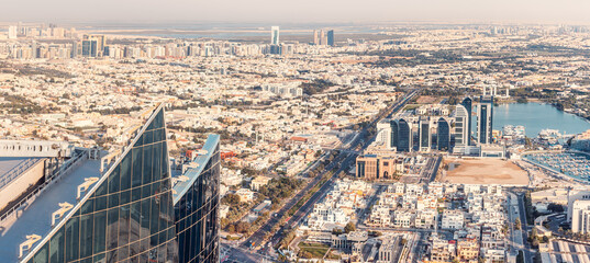 Aerial view of a wide street with car traffic among skyscrapers with hotels and residential real estate blocks in Abu Dhabi, UAE - obrazy, fototapety, plakaty