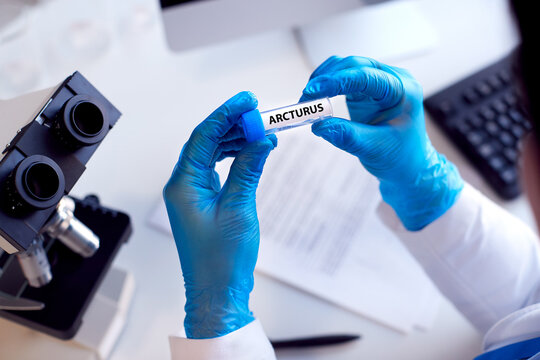 Close Up Of Lab Worker Conducting Research Using Microscope Holding Test Tube With Arcturus